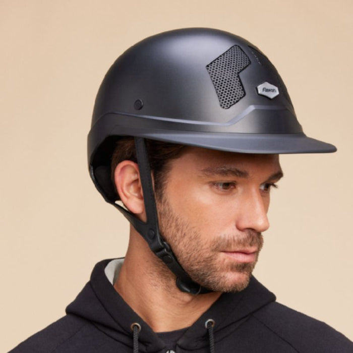 Casque d'équitation armet Flex on pour cavalier. Visière mixte. Model noir mat, jugulaire noire portée par un homme. Vendu par fouilhoux fontainebleau