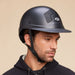 Casque d'équitation armet Flex on pour cavalier. Visière mixte. Model noir mat, jugulaire noire portée par un homme. Vendu par fouilhoux fontainebleau